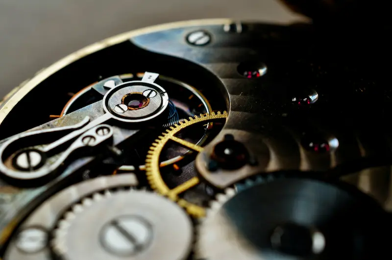An extreme close-up of the intricate inner gears, balance wheel, and jewels of a mechanical watch movement