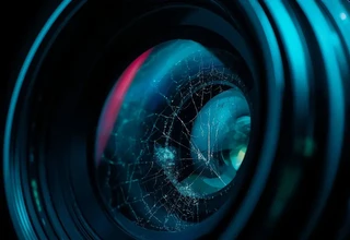 Close-up of a premium camera lens with visible spiderweb-like lens fungus etching the internal glass element, illustrating how to prevent camera lens fungus