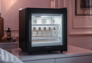 A premium black skincare mini fridge used as a temperature-controlled storage solution for luxury perfumes.