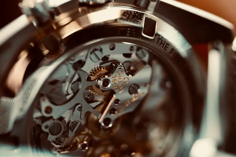 A detailed macro photograph showing the open sapphire caseback of an Omega chronograph watch, revealing the Omega Calibre 3861 mechanical movement