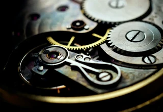 An extreme macro shot of a mechanical watch movement showing the balance wheel assembly, hairspring, ruby jewels, and metallic gears in intricate detail
