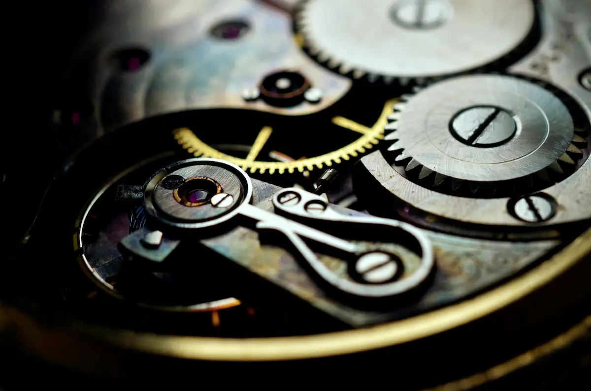 An extreme macro shot of a mechanical watch movement showing the balance wheel assembly, hairspring, ruby jewels, and metallic gears in intricate detail