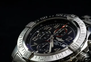 Macro close-up of a Breitling chronograph watch highlighting its stainless steel unidirectional rotating bezel with minute markers