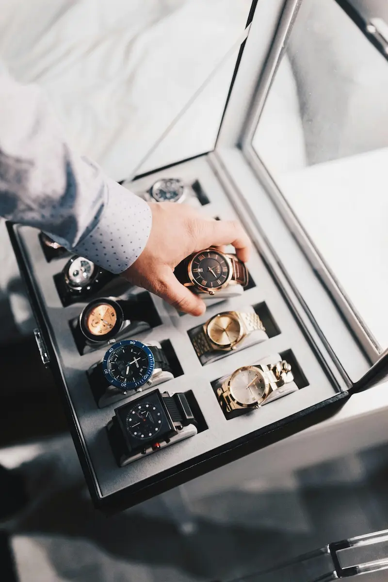 A collector carefully handling a luxury watch from a premium watch box, representing proper asset management and documentation of high-value timepiece collections