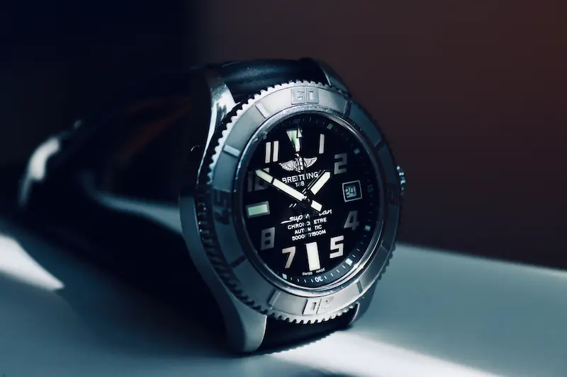Macro shot of a Swiss automatic luxury diver watch with a stainless steel bezel and black dial on a dark surface