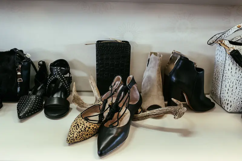 A curated display of women's quiet luxury footwear including cheetah print lace-up flats, black studded pumps, and leather ankle boots on a shelf