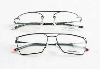 Two pairs of metal designer eyeglasses with lens logo print laying on a white surface for authenticity comparison