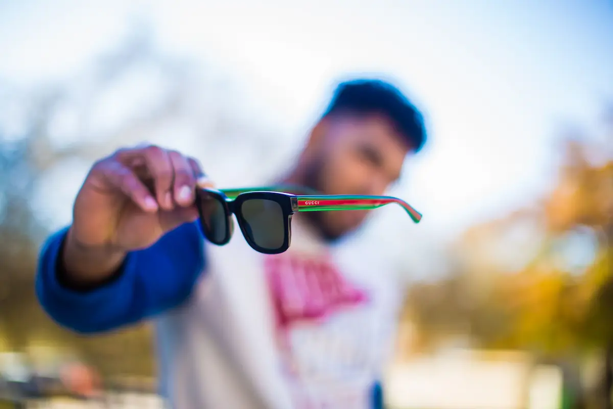 A close-up view of handling luxury Gucci sunglasses properly to prevent frame misalignment and maintain lens quality