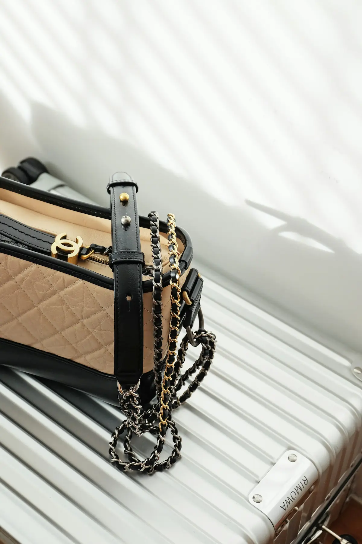 Chanel quilted handbag with iconic CC logo and gold chain strap resting on a luxury suitcase, symbolizing high-end travel and investment-worthy accessory care