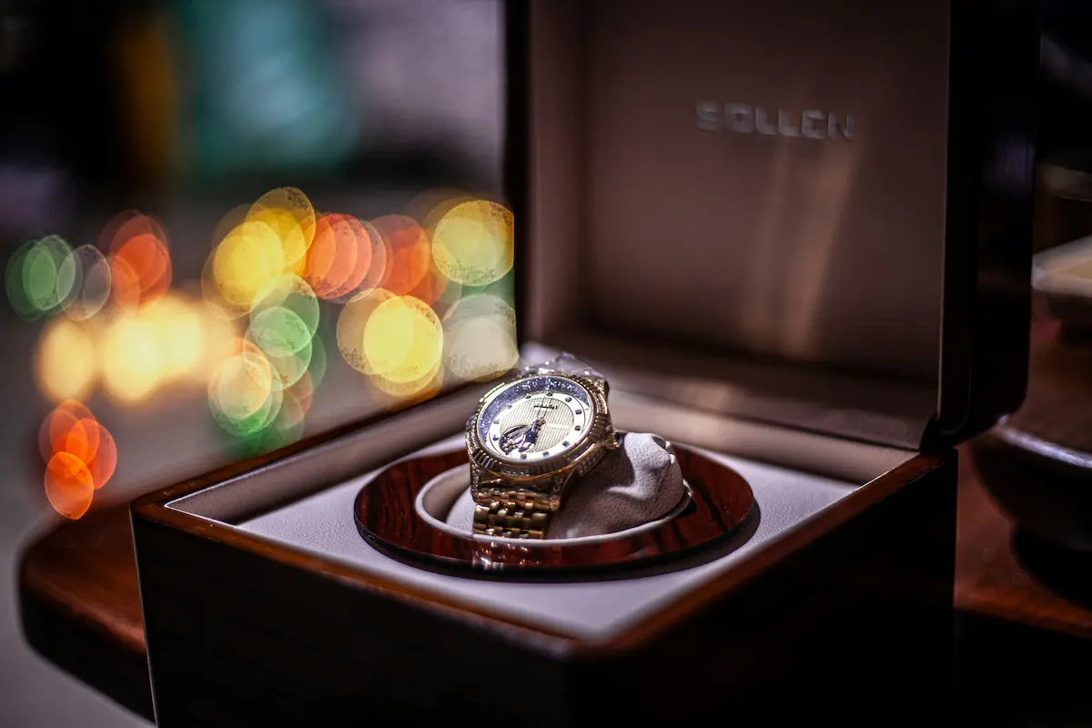 Luxury automatic watch winder displaying a gold timepiece in a premium wooden case, representing professional horological storage solutions for high-value watch collections