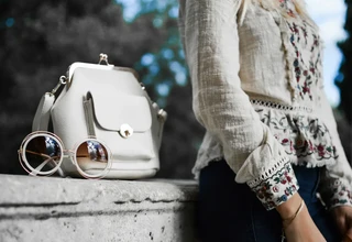 Light colored leather handbag outdoors showing vulnerability to water stains requiring immediate proper treatment to prevent permanent marks