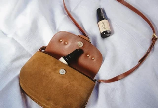 Tan suede and leather crossbody purse on natural linen background showing different leather textures that require gentle natural cleaning methods