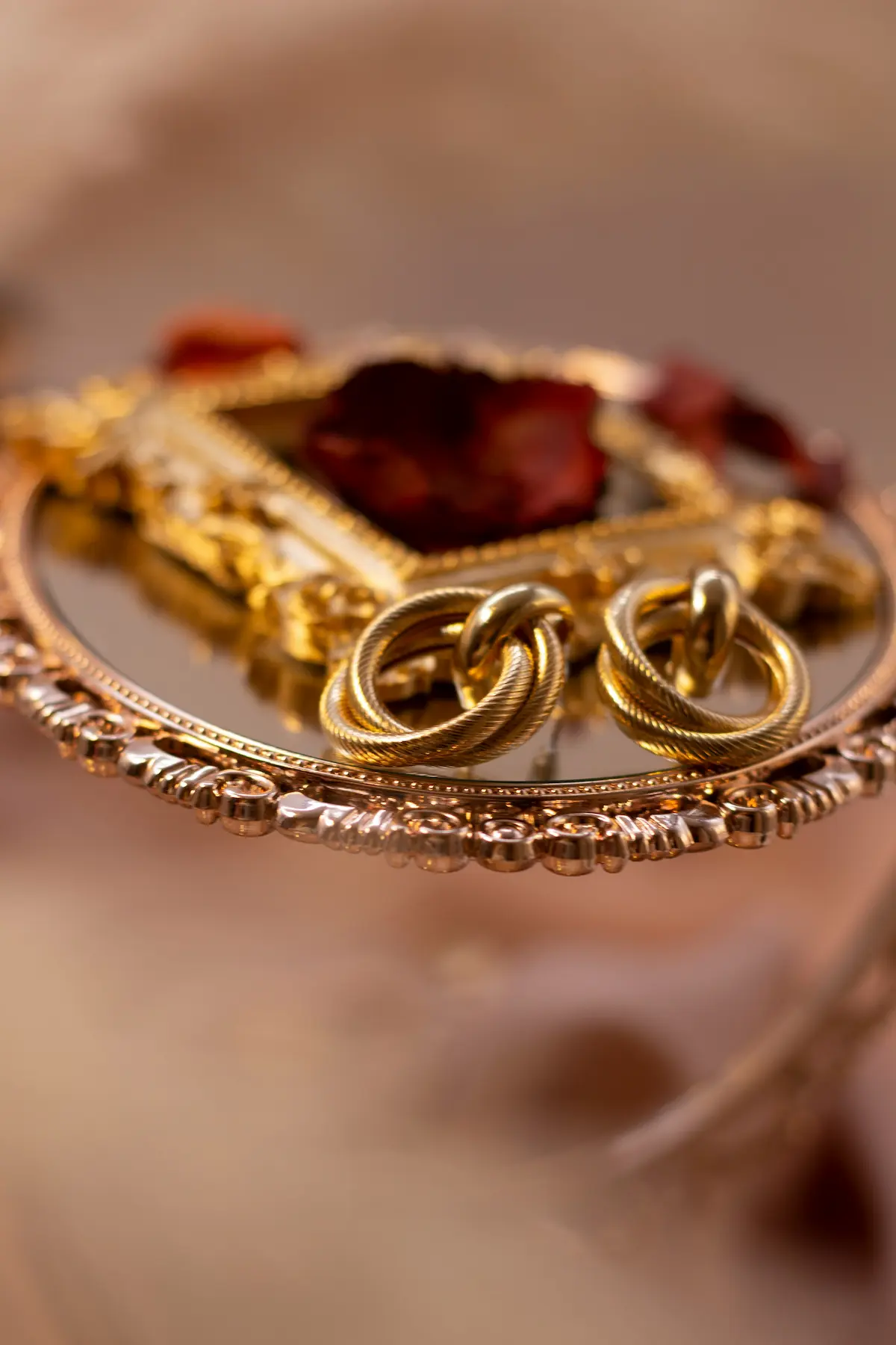 Gold jewelry pieces including twisted rings displayed on an ornate gold mirror tray, representing fine gold accessories that require proper tarnish removal and home cleaning techniques to restore their natural brilliance