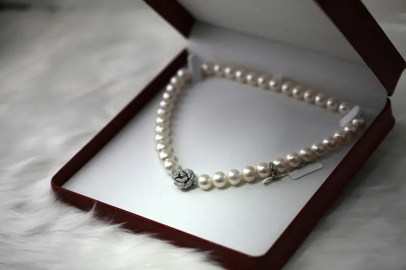 Fine pearl necklace with silver floral clasp stored properly in a velvet jewelry box, representing the correct storage method that protects pearl luster and prevents surface damage between wearing
