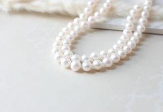 Lustrous white pearl necklace displayed on a clean cream surface showing the natural iridescent glow that proper gentle cleaning techniques help preserve without damaging the delicate nacre