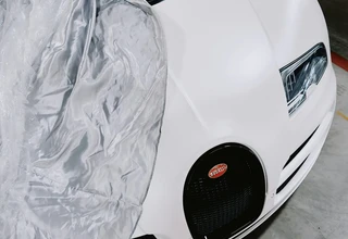 A white Bugatti Veyron supercar partially covered in a garage, representing high-value luxury goods and premium assets