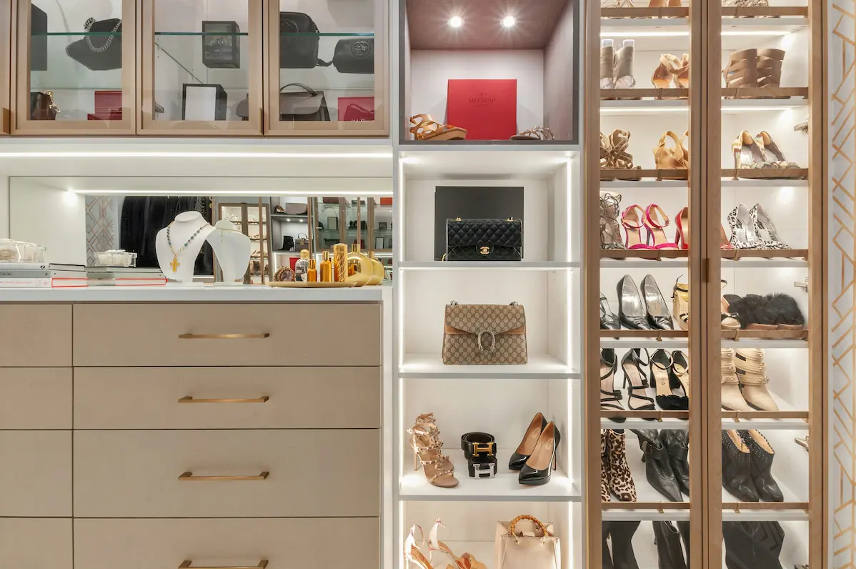 A well-organized luxury closet displaying designer shoes, handbags, and jewelry on illuminated shelves, representing a curated quiet luxury fashion collection