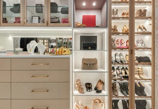 A well-organized luxury closet displaying designer shoes, handbags, and jewelry on illuminated shelves, representing a curated quiet luxury fashion collection