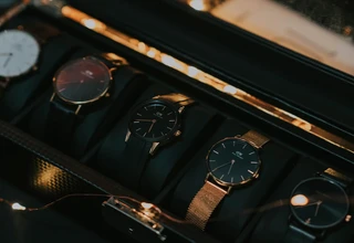 Multiple minimalist Daniel Wellington watches with leather and mesh straps neatly stored in a dark luxury watch box, representing the best watch storage solution