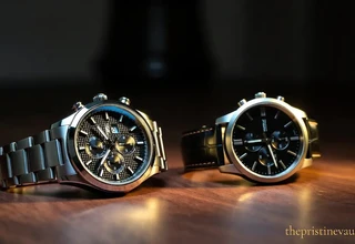 Two chronograph watches side by side on a wooden surface — a stainless steel bracelet watch and a leather strap watch — illustrating the key differences between a luxury watch and a fashion watch