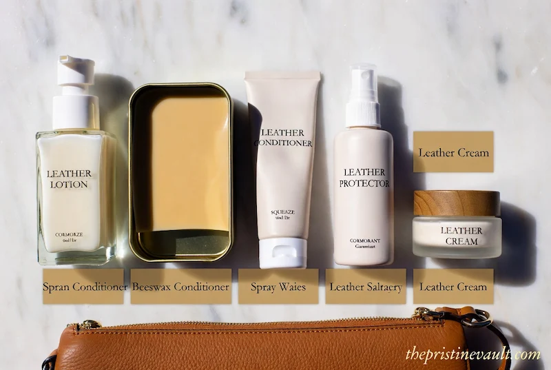 A variety of premium leather care products, including lotions and balms, arranged on a marble surface above a brown leather bag, illustrating the best conditioner for handbag maintenance.