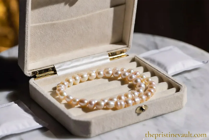 Cream velvet jewelry box with gold hinges holding a pink  freshwater pearl necklace — best jewelry box for storing pearls