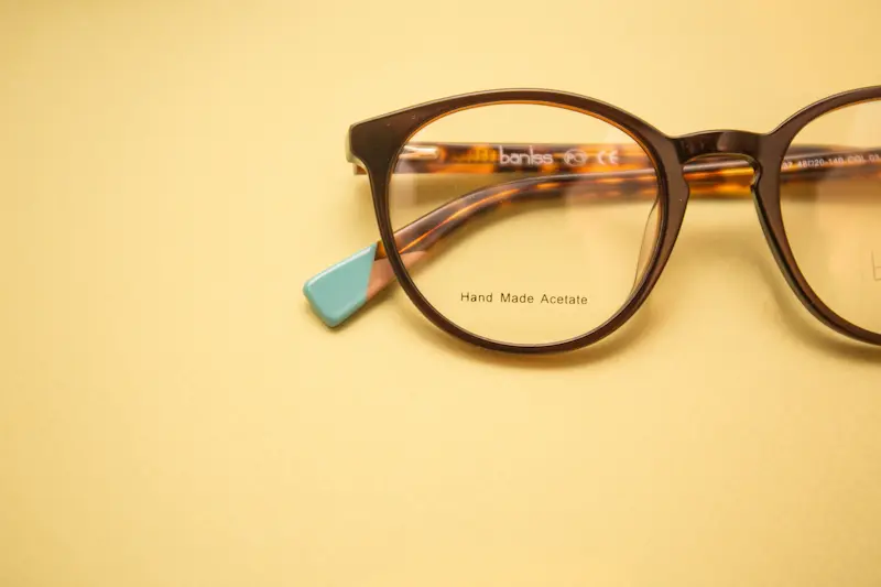Close-up of a premium brown handmade acetate women's eyeglass frame with turquoise temple tips on a yellow background