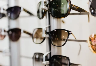 A close-up display stand showcasing designer sunglasses and prescription eyeglass frames inside an optical store