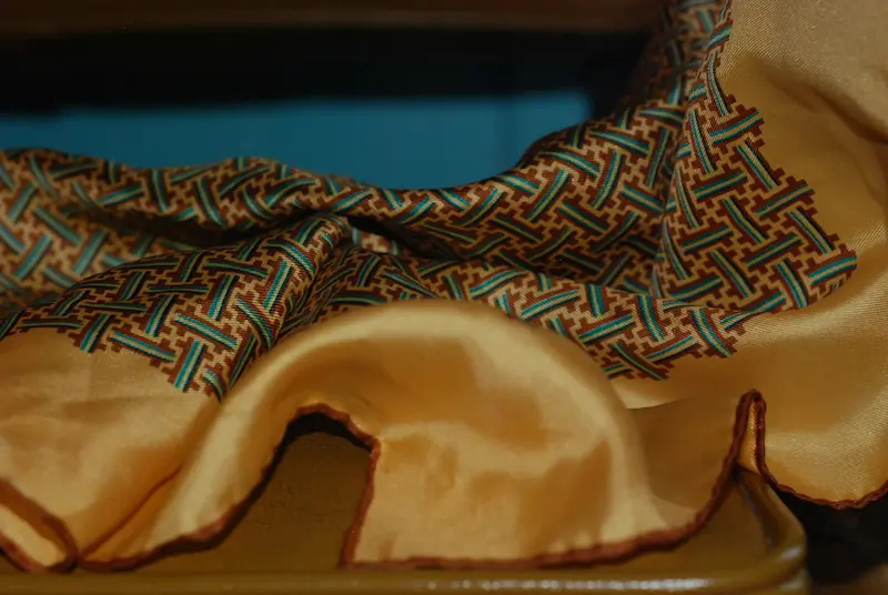 Luxurious gold silk scarf with decorative border showing natural fabric drape and fold texture