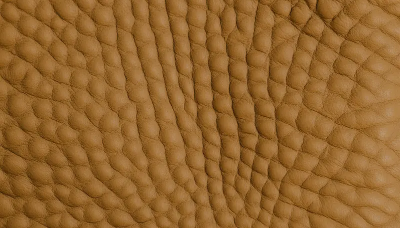 A high-resolution macro shot of Hermès Togo leather, highlighting the natural pebbled grain and veining characteristic of high-quality calfskin